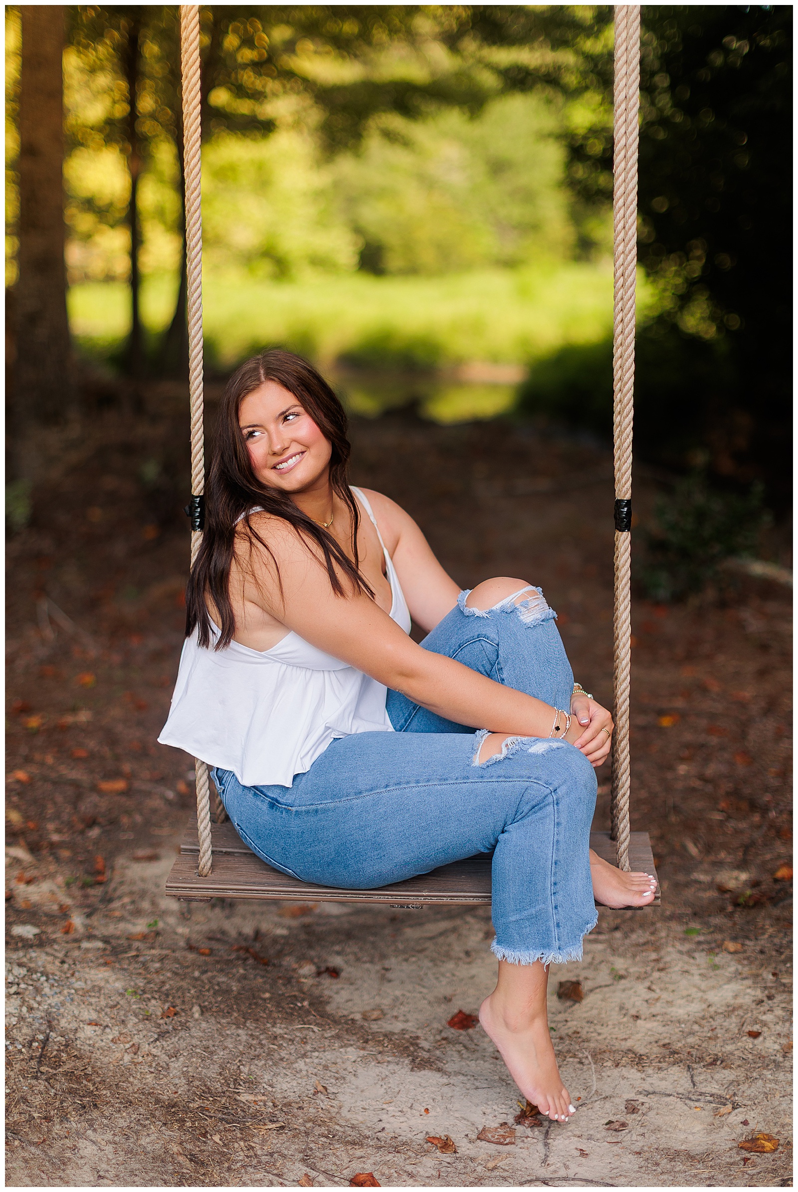 Senior girl pictures in white tank top and jeans at farm fence at The Farmer’s Daughter at Walston Pond in North Carolina.